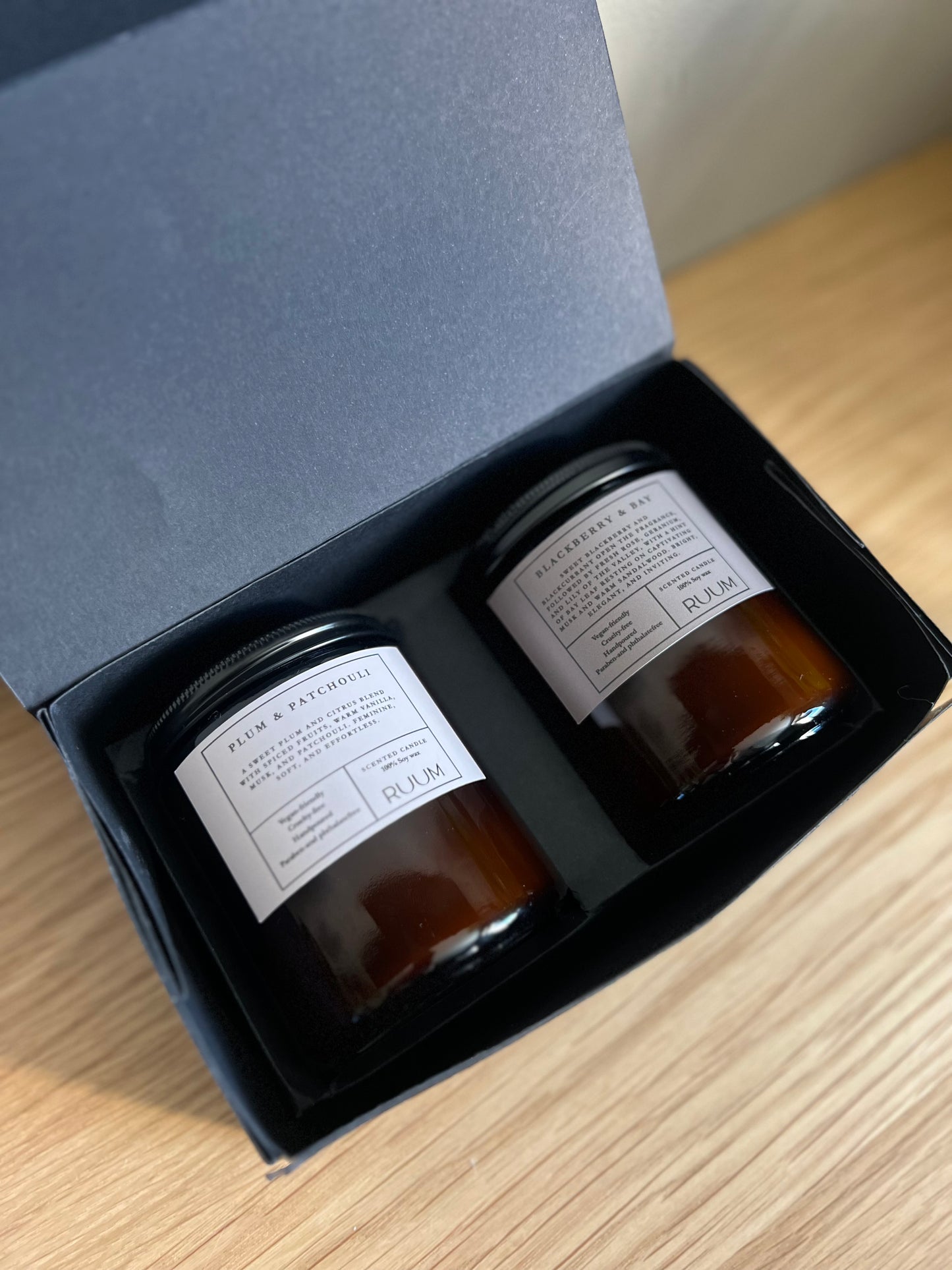 Two jars with labels inside an open blue box on a wooden surface
