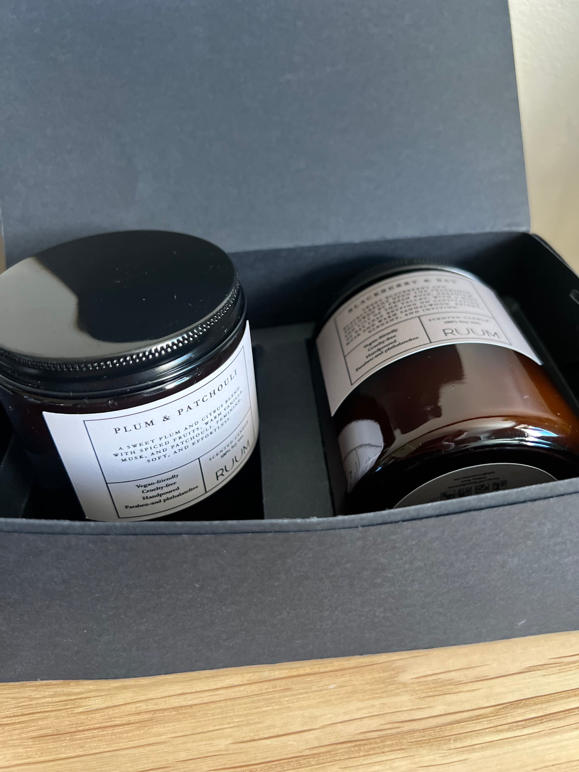 Two jars with labels inside a gray box on a wooden surface
Ruum_ Soywax Scented Candle