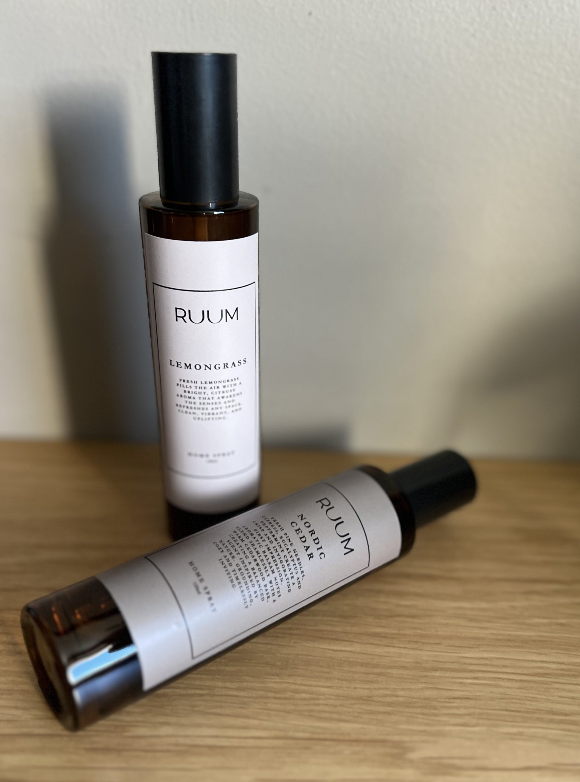 Two RUUM home sprays on a wooden surface with a neutral background